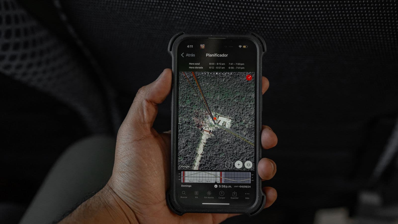 Hand holding a smartphone showing a GPS map inside a car
