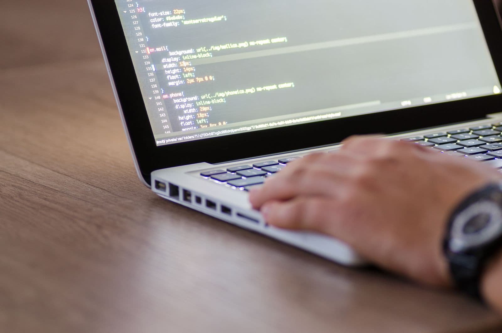Person coding on a laptop with HTML code on the screen
