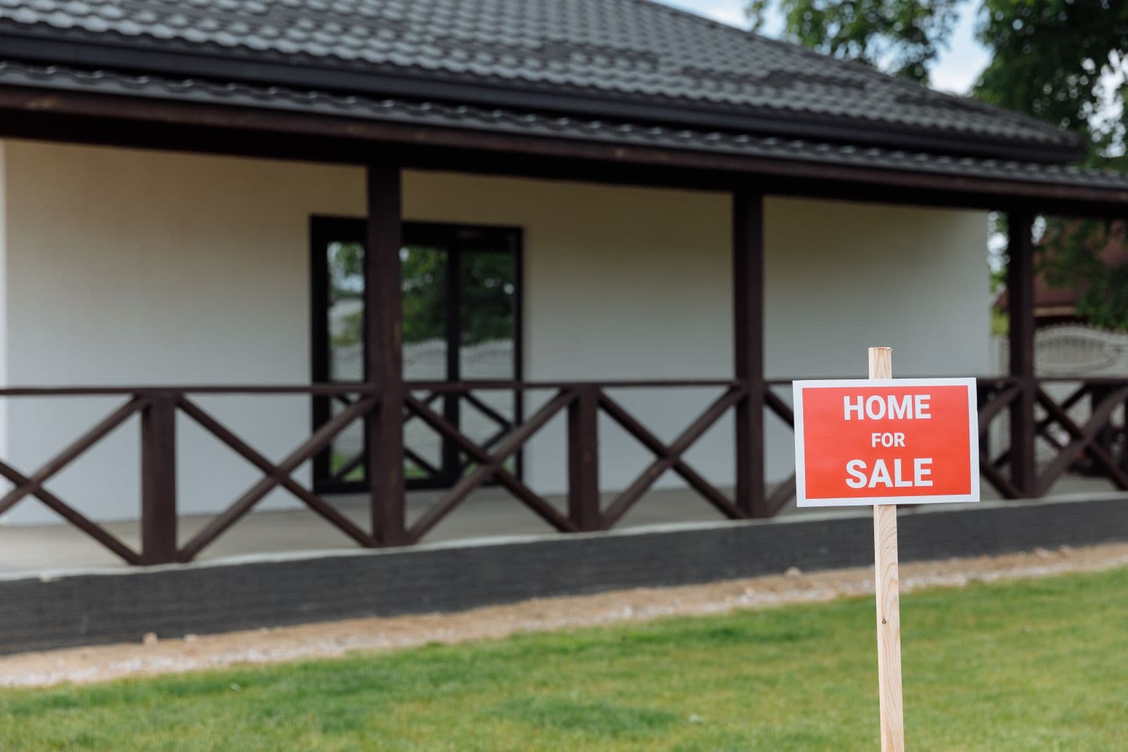 White house with a red and white Home for Sale sign on the lawn
