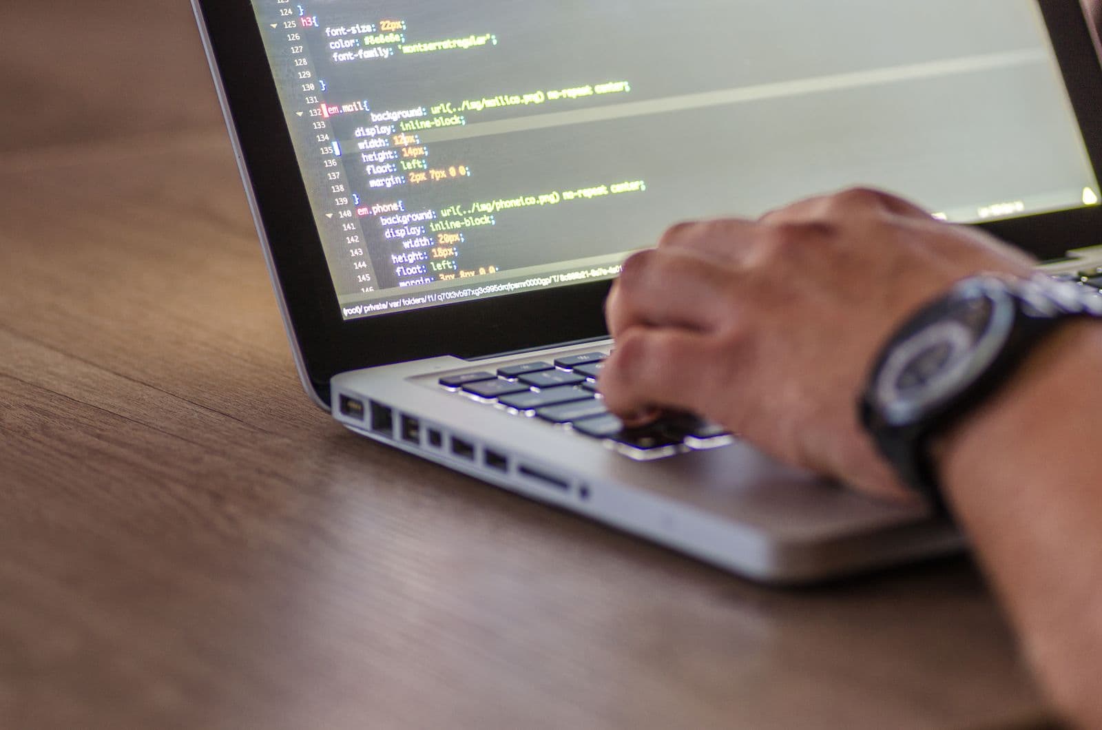 Close-up of hands typing code on a laptop keyboard