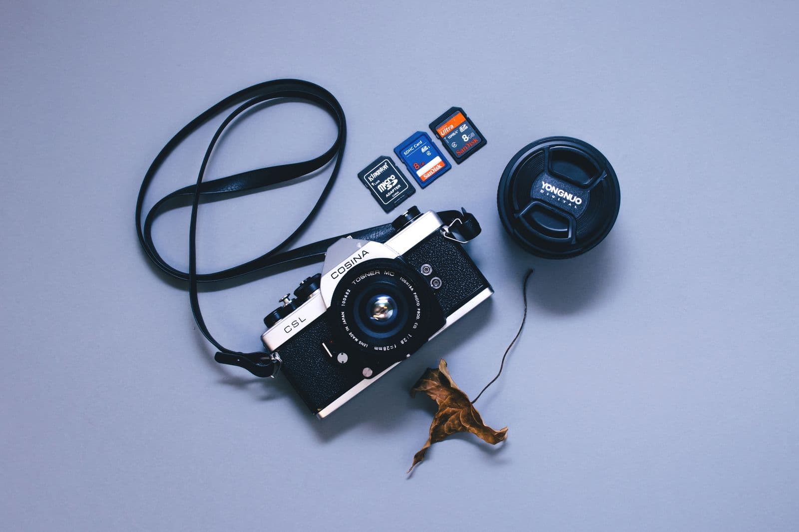 Flat lay of a vintage camera with memory cards and lens cap