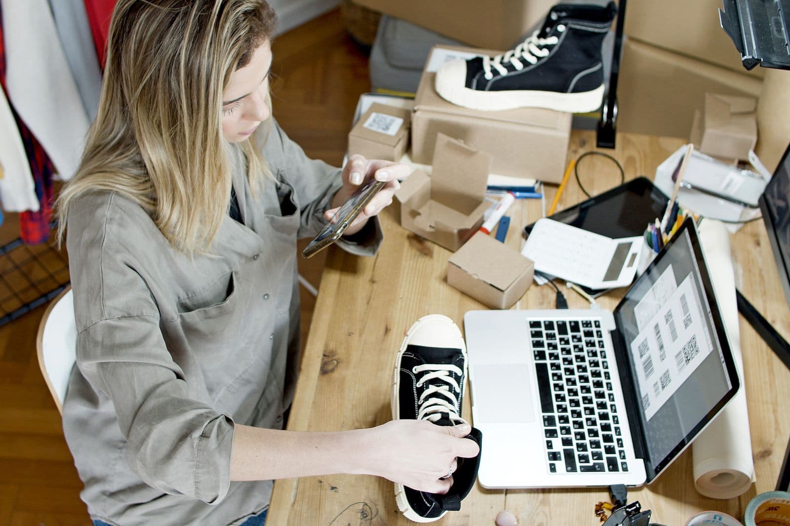 Woman photographing shoes for an online listing at home