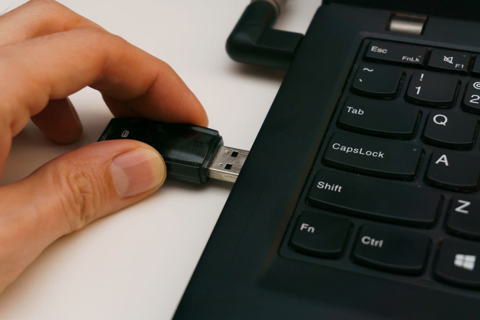 Fingers inserting a USB drive into a laptop's port