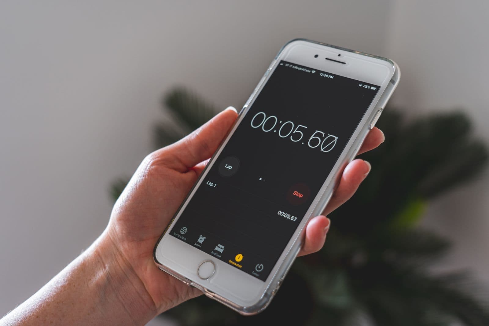 Close-up of a hand holding a silver iPhone showing an app