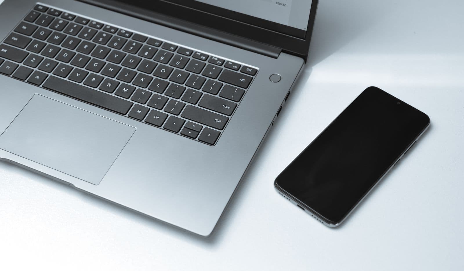Laptop and smartphone side by side on a white desk