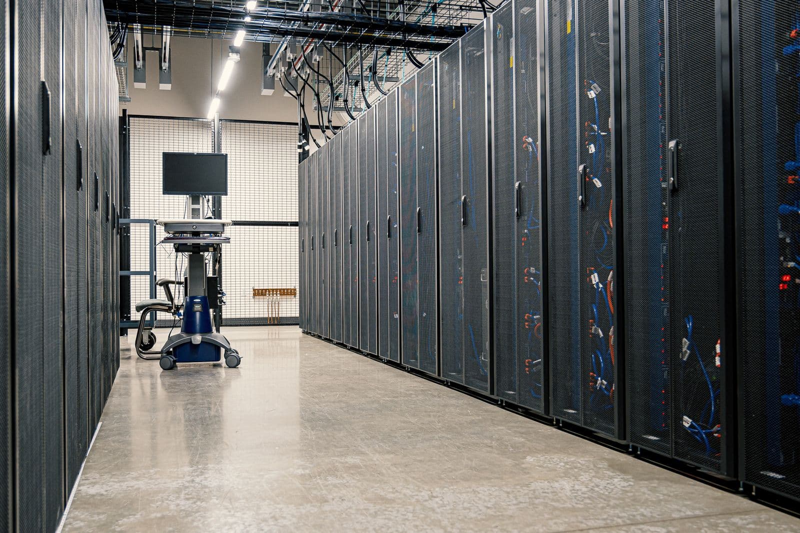 Rows of server racks and cables in a data center corridor