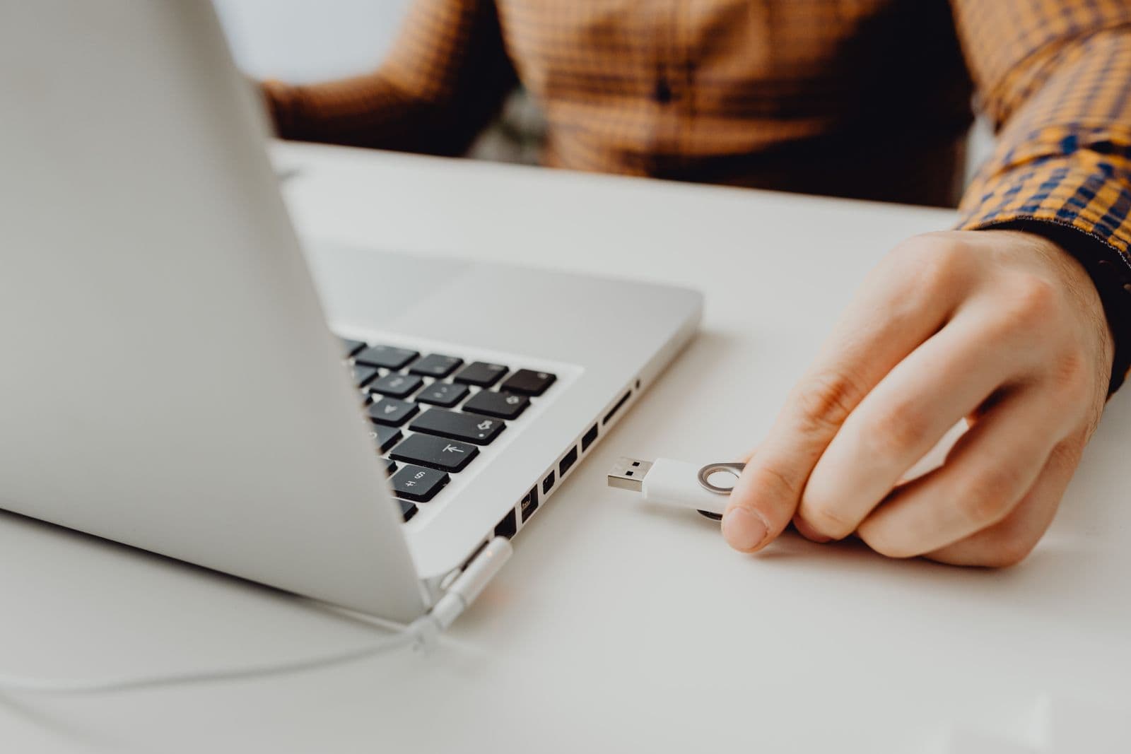 Hand inserting a USB flash drive into a laptop port